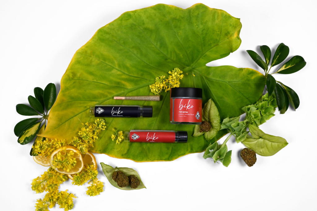 red biko jars and a joint nestled in a large green oval leaf adorned by lemon slices smaller dark green leaves and little yellow flowers