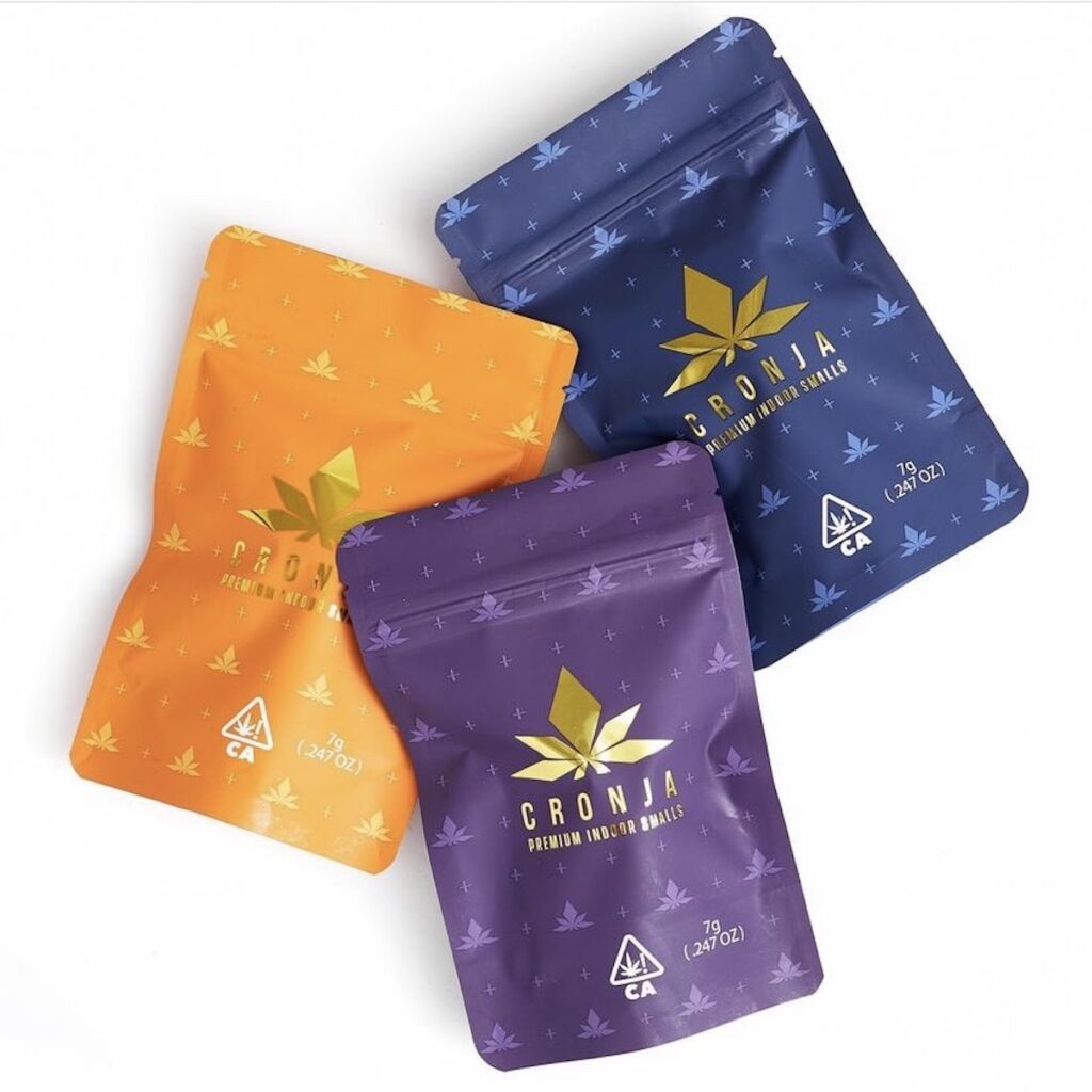 Cronja Culture flower packages in orange dark purple and navy blue with gold labels featuring the top of a cannabis leaf