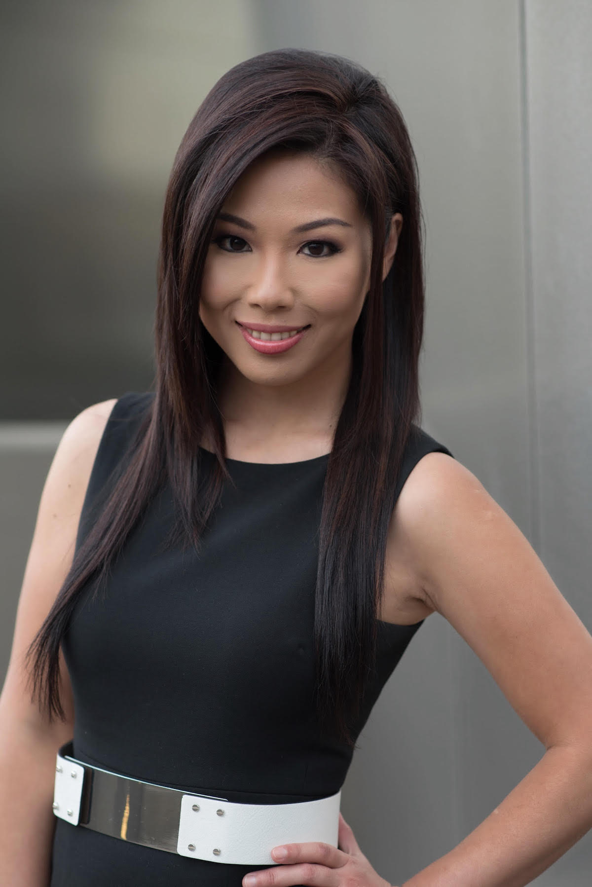Headshot of Alice Kuo with her hand on her hip she has long black hair is smiling softly and wearing a black sleeveless top