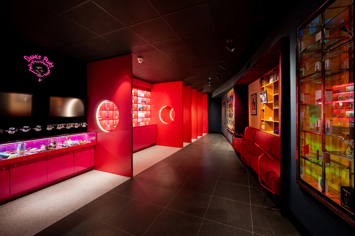 a red dispensary interior with black floors and illuminated product lining the wallls