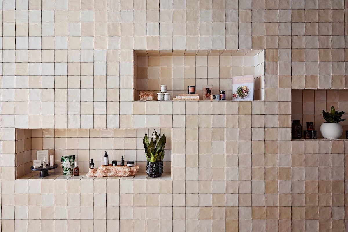 tiled wall with embedded display shelves holding neutral toned products