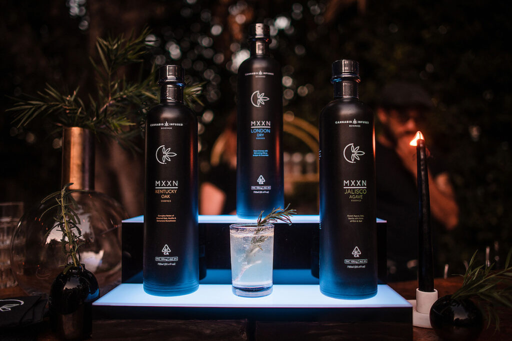 backbar display of black MXXN bottles arranged in a triangle and lit from below in bright blue florescent light 