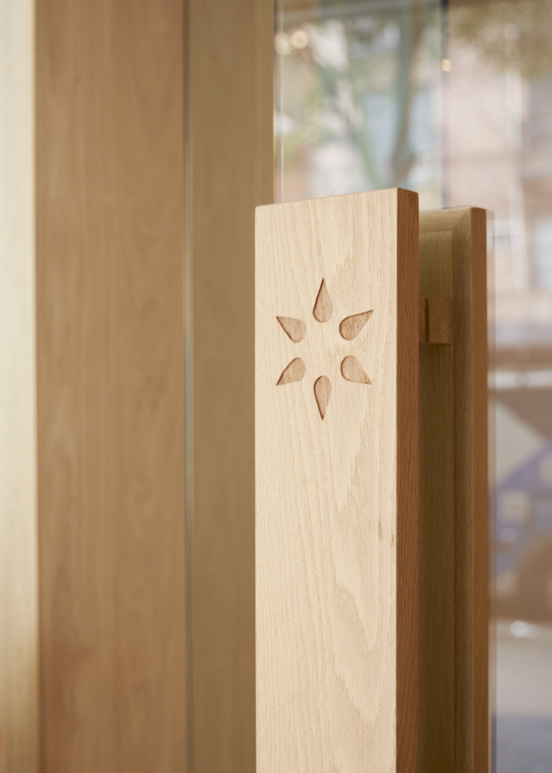 etain door handle in light wood on a glass door