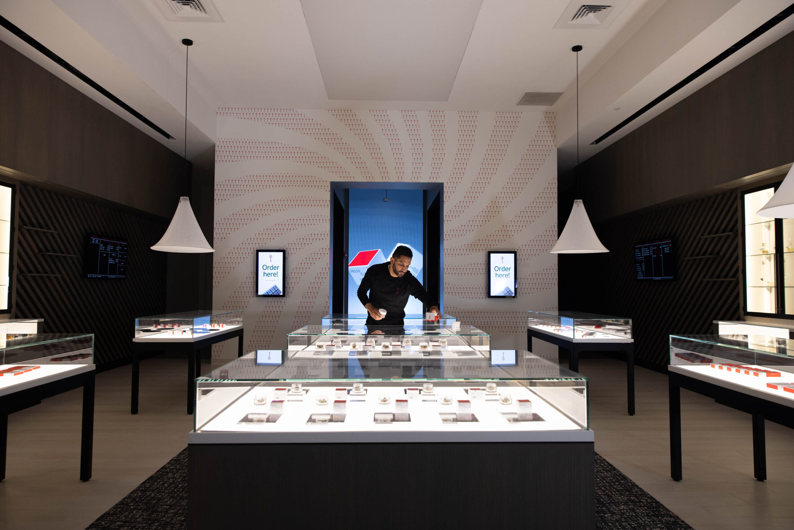 dispensary interior with black walls and white floors with an industrial chic chandelier and product display on the back wall