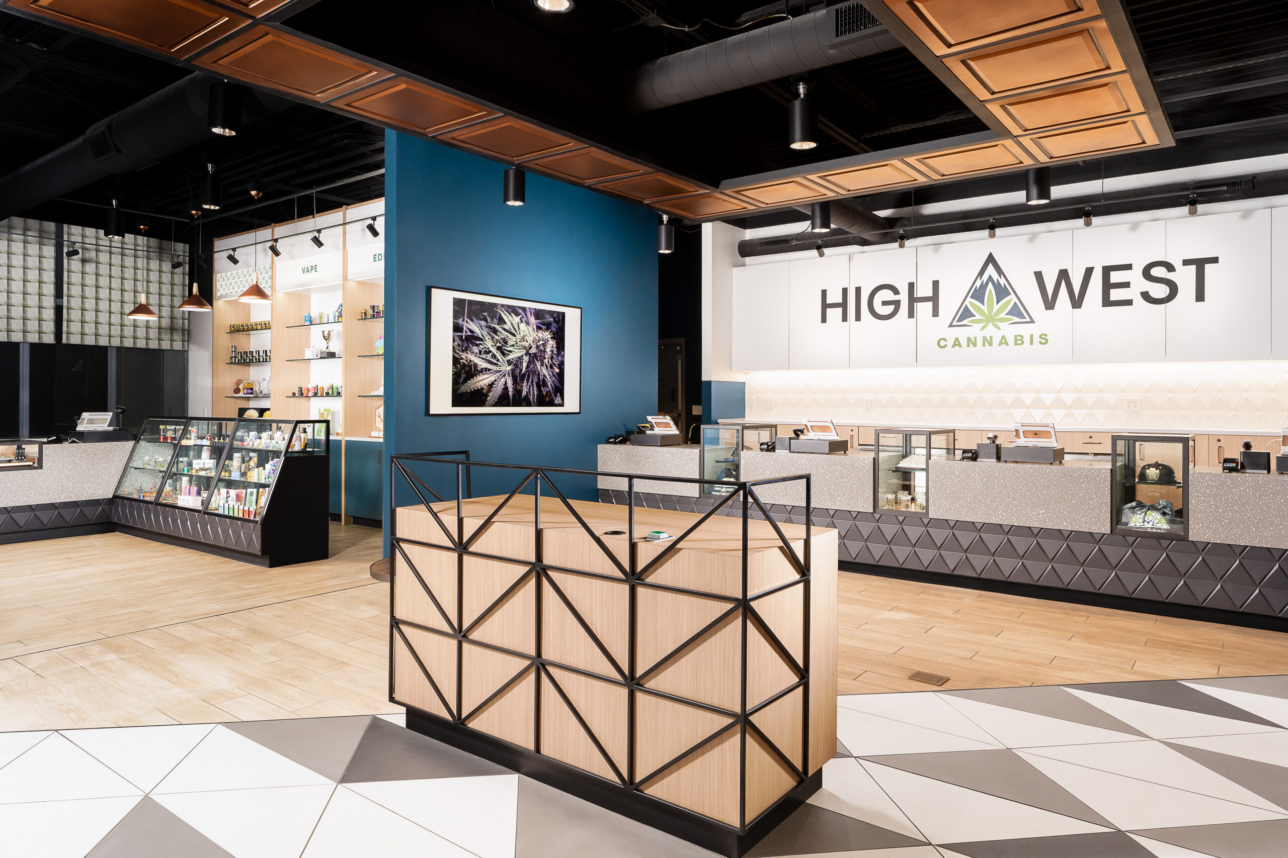 dispensary interior with wood floors and black ceiling high west logo is in black on a wall behind a display counter