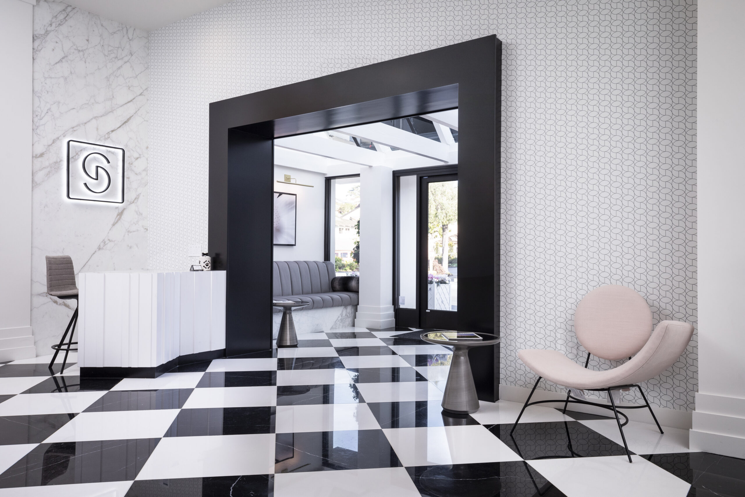 white room with black and white tiled floor and a light pink chair and white desk